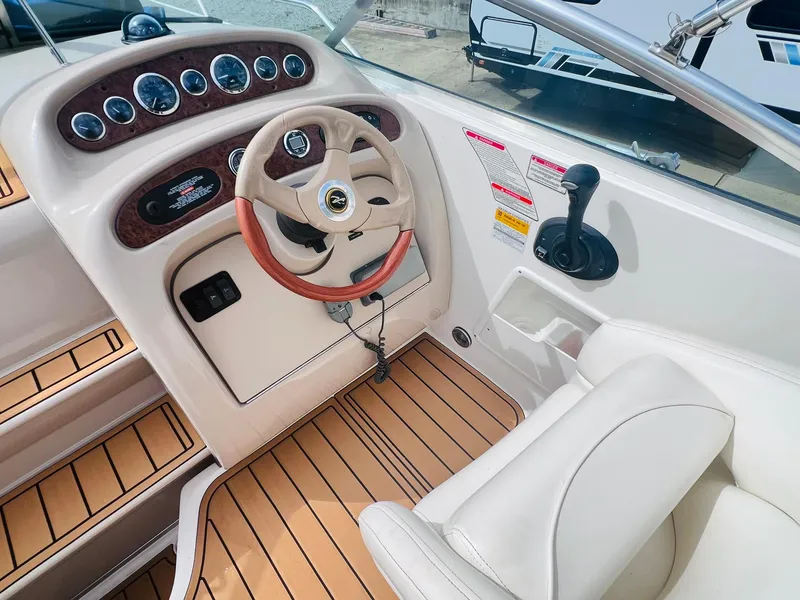 Slide: The Image of 2001 Sea Ray 260 Sundancer helm with wood accents and beige seating. - 11