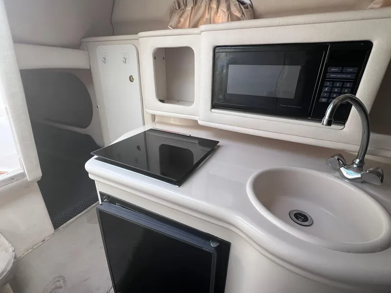 Slide: The Image of 2001 Sea Ray 260 Sundancer interior kitchen with sink, stove, and microwave. - 20