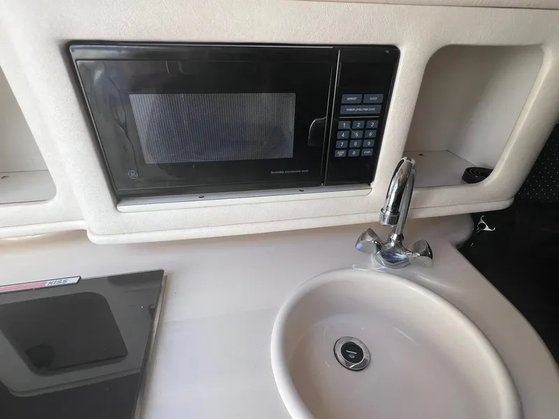 Slide: The Image of 2001 Sea Ray 260 Sundancer kitchenette with microwave, sink, and faucet. - 23