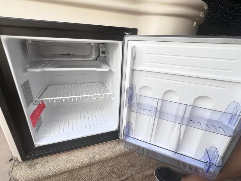 Slide: The Image of Open mini fridge inside 2001 Sea Ray 260 Sundancer boat, showing empty shelves and door storage. - 24