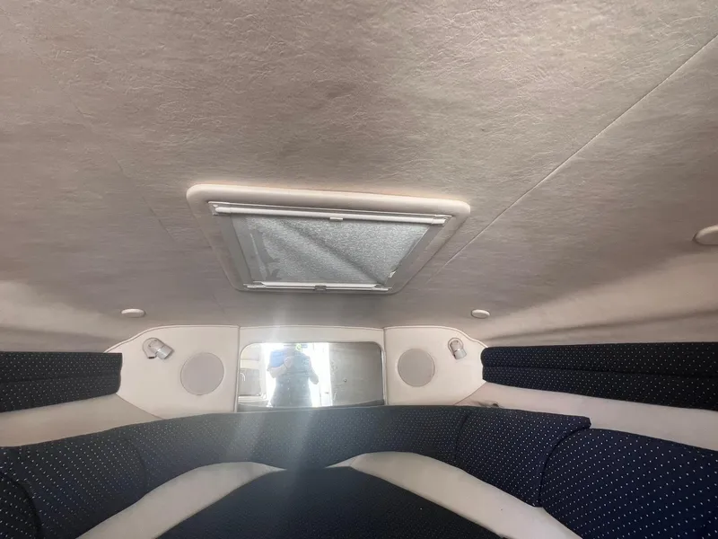 Slide: The Image of Interior cabin of a 2001 Sea Ray 260 Sundancer boat, featuring cushioned seating and a ceiling hatch. - 25