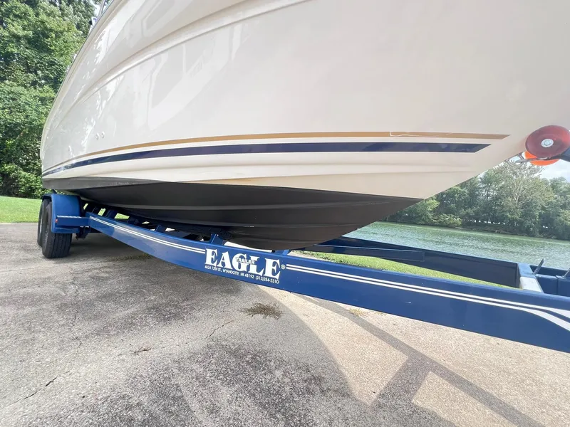Slide: The Image of 2001 Sea Ray 260 Sundancer on blue Eagle trailer, parked near a lake. - 3