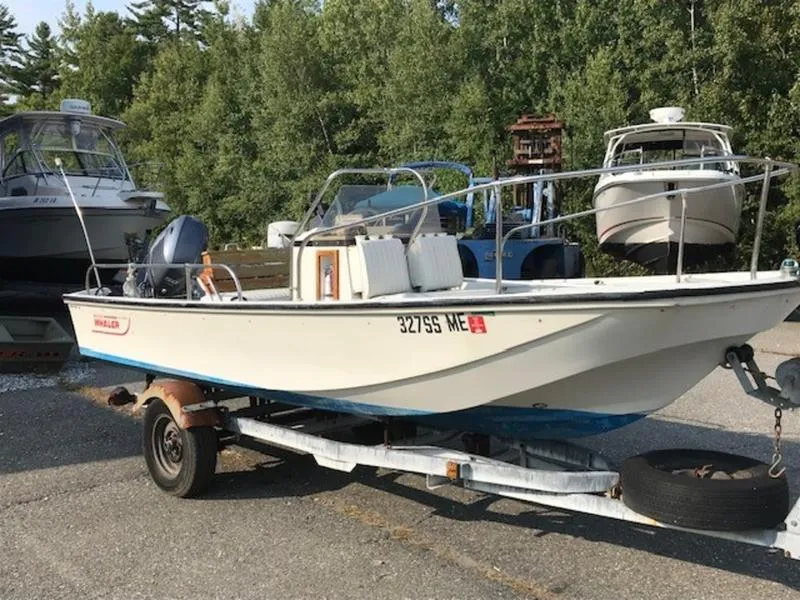 Slide: The Image of 1988 Boston Whaler 170 Montauk boat on trailer, parked outdoors near other boats. - 3