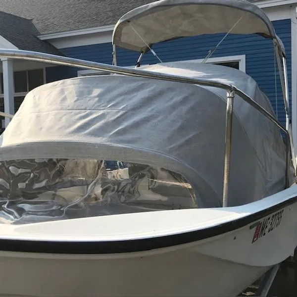 Slide: The Image of 1988 Boston Whaler 170 Montauk boat with protective cover, docked near blue building. - 5
