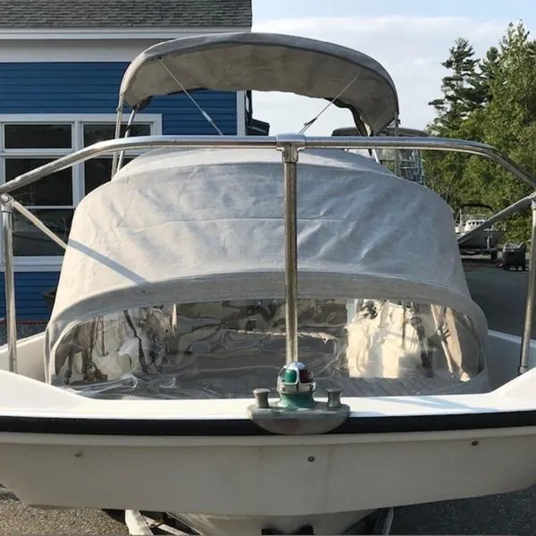 Slide: The Image of 1988 Boston Whaler 170 Montauk boat with canopy, docked near blue building. - 9