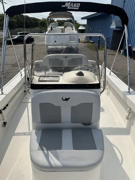 Slide: The Image of 2019 Mako 180 CC boat with canopy and seating, docked near blue building. - 3