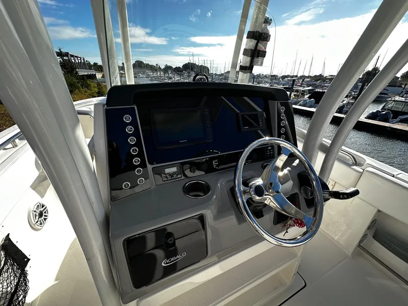 Slide: The Image of 2021 Robalo R242 Center Console boat dashboard with steering wheel, marina view. - 8