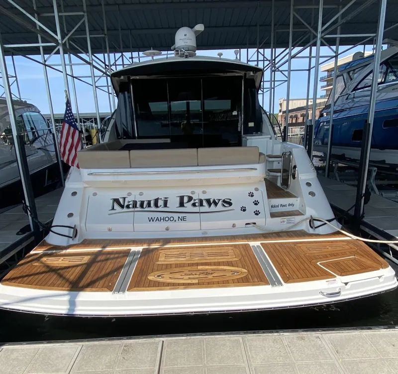 Slide: The Image of 2015 Sea Ray 510 Sundancer yacht named "Nauti Paws" docked with American flag. - 1
