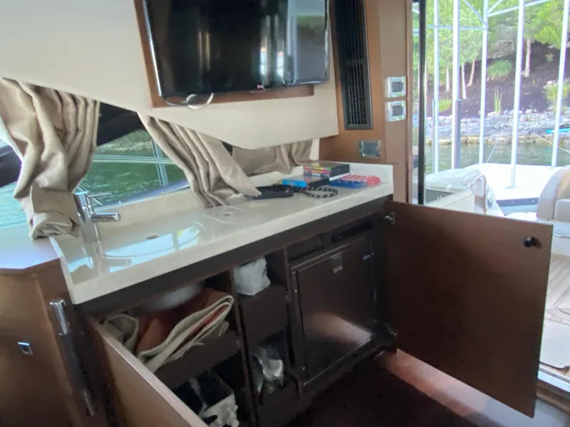 Slide: The Image of Interior of 2015 Sea Ray 510 Sundancer yacht with open cabinets and TV. - 30