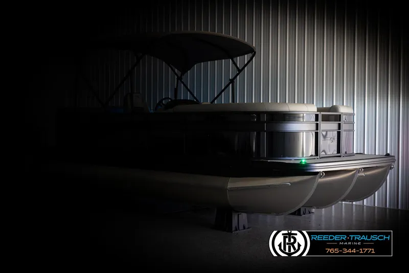 Slide: The Image of 2025 Bennington 23 SXPDSE pontoon boat in dimly lit indoor storage. - 4