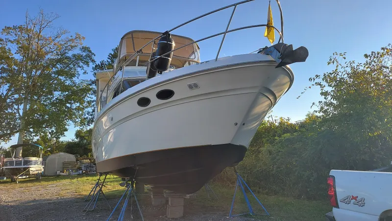 Slide: The Image of 2000 Sea Ray 380 Aft Cabin yacht on stands, surrounded by trees and vehicles. - 1