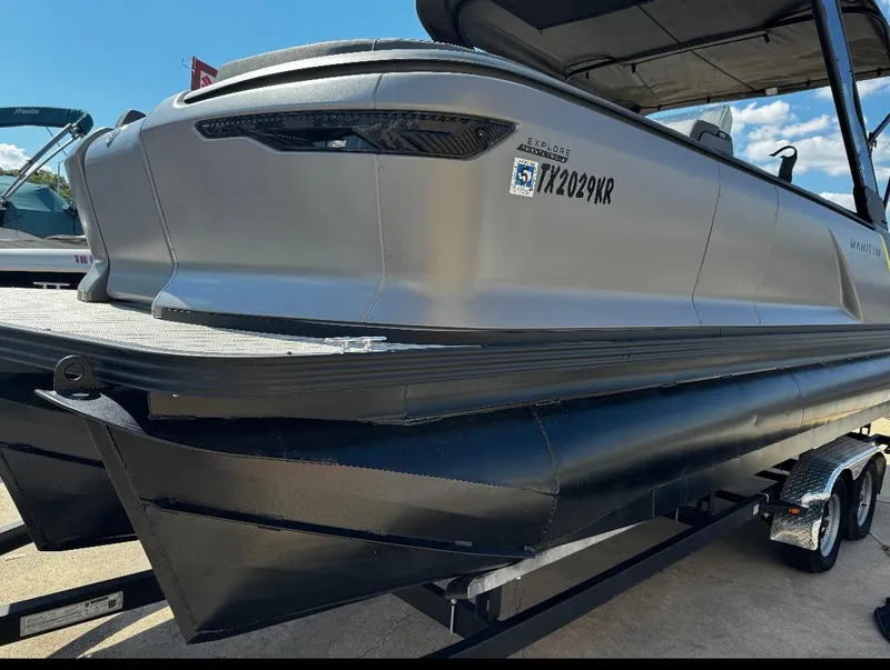 Slide: The Image of 2024 Manitou Explore pontoon boat on trailer, sleek design, silver finish. - 2