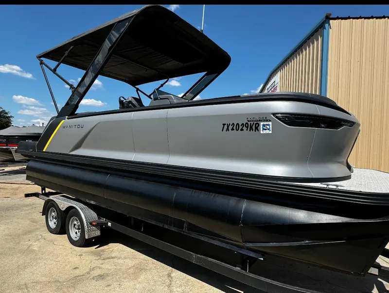 Slide: The Image of 2024 Manitou Explore pontoon boat on trailer, featuring sleek design and canopy. - 4