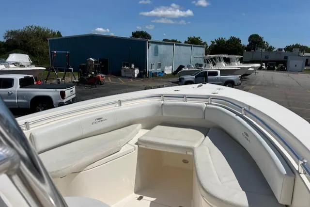 Slide: The Image of 2021 Cobia 237 Center Console boat with spacious seating, parked near a blue warehouse. - 22