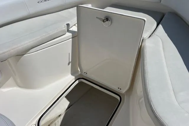 Slide: The Image of 2021 Cobia 237 Center Console boat storage compartment with open hatch and cushioned seating. - 23
