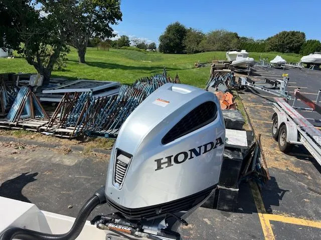 Slide: The Image of 2021 Cobia 237 Center Console with Honda outboard motor in a boatyard setting. - 5