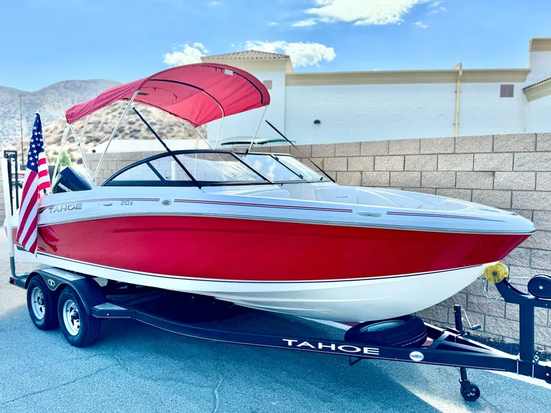 Slide: The Image of 2022 Tahoe 210 S boat with red canopy on trailer, American flag displayed. - 1