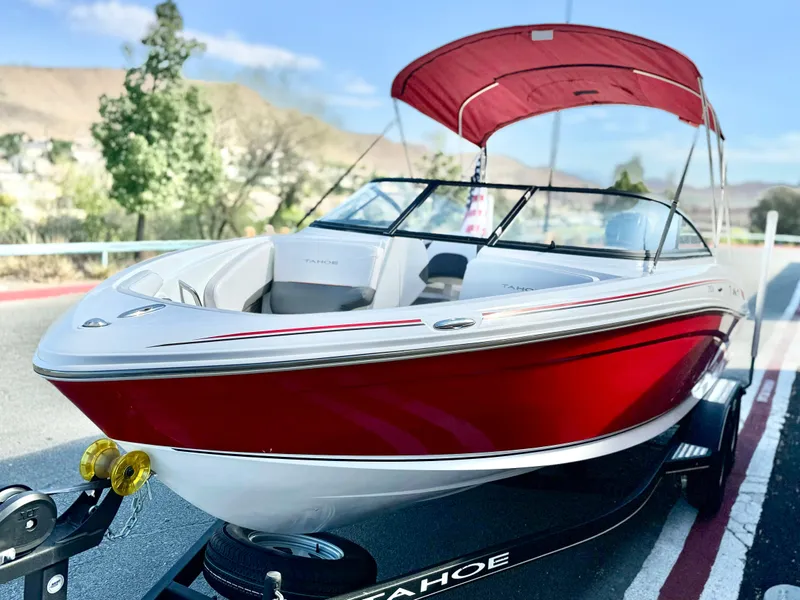 Slide: The Image of 2022 Tahoe 210 S boat with red canopy on trailer, parked outdoors. - 4