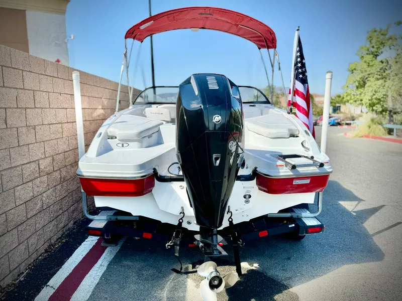 Slide: The Image of 2022 Tahoe 210 S boat with outboard motor and American flag, parked on street. - 5