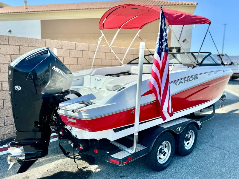 Slide: The Image of 2022 Tahoe 210 S boat with red canopy and American flag on trailer. - 6