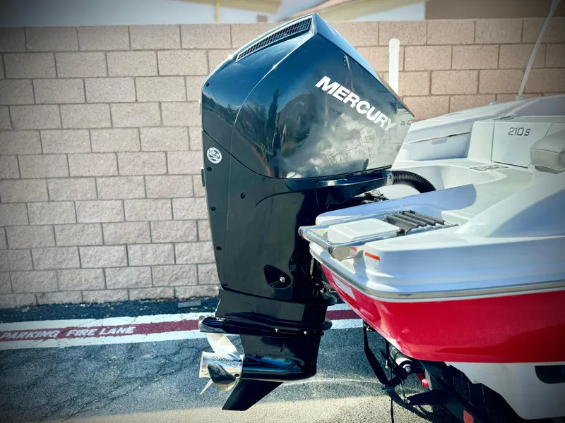 Slide: The Image of 2022 Tahoe 210 S boat with Mercury outboard motor, parked near brick wall. - 7