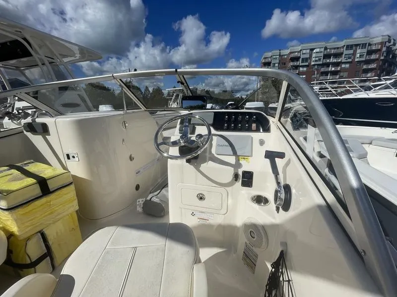 Slide: The Image of 2017 Grady-White 205 Freedom boat interior with steering wheel and controls under a blue sky. - 3
