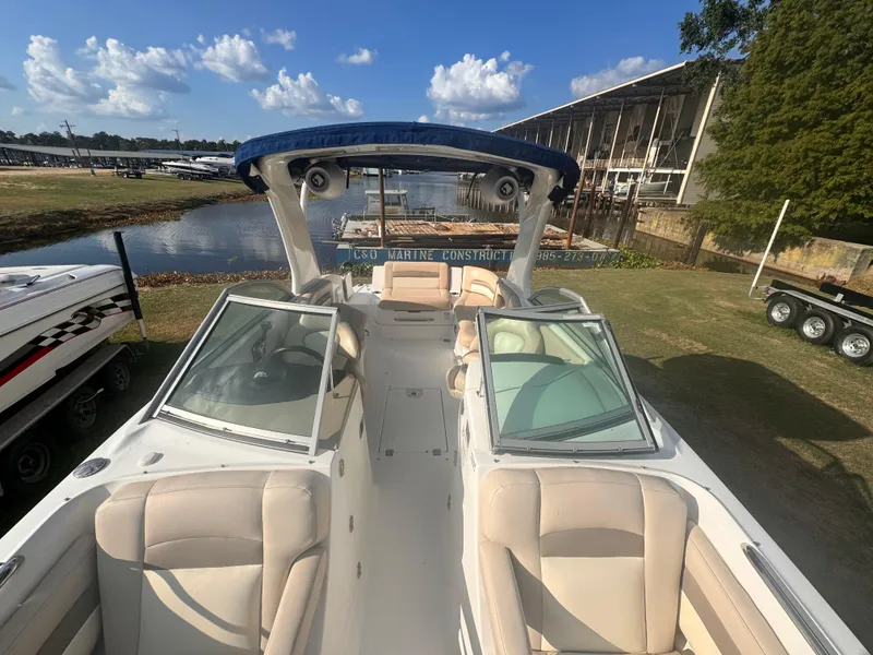 Slide: The Image of 2012 Chaparral 264 Sunesta boat with spacious seating, docked near a marina under a clear sky. - 4