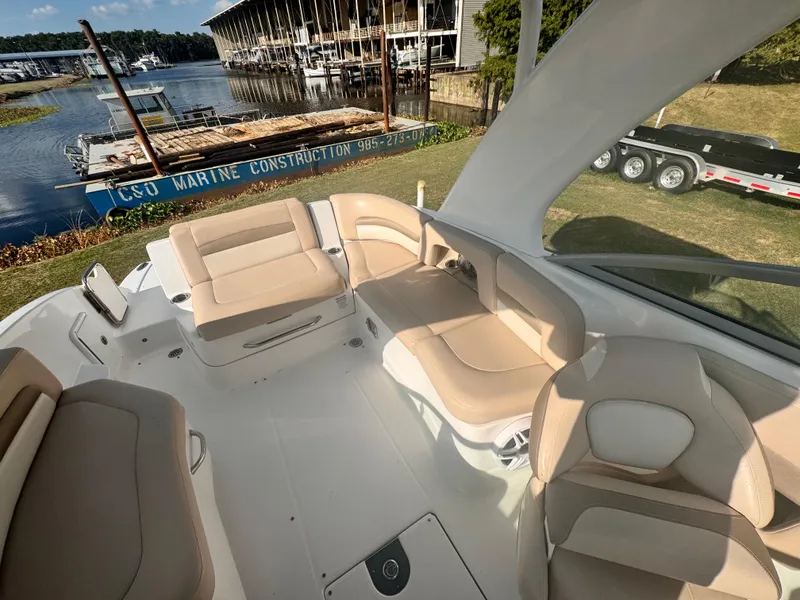 Slide: The Image of 2012 Chaparral 264 Sunesta boat interior with beige seating near marina. - 5