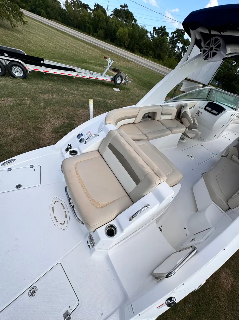 Slide: The Image of 2012 Chaparral 264 Sunesta boat interior with beige seating and trailer in background. - 8