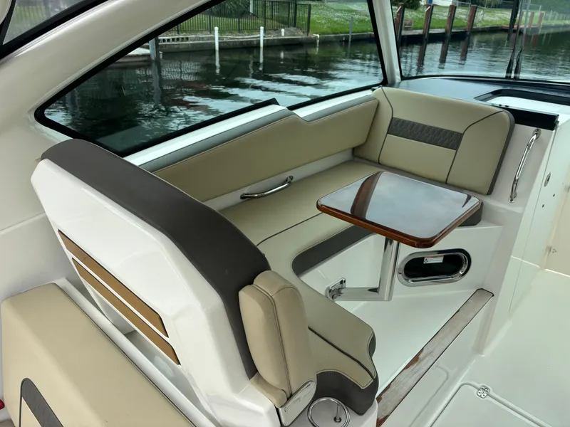 Slide: The Image of 2020 Pursuit 325 Dual Console boat interior with seating and table by the water. - 13