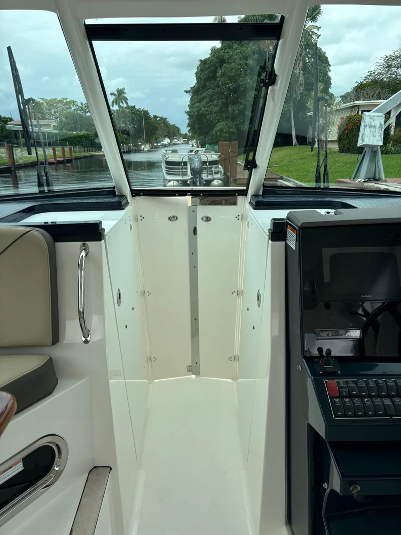 Slide: The Image of 2020 Pursuit 325 Dual Console boat interior with open windshield, docked by a canal. - 26