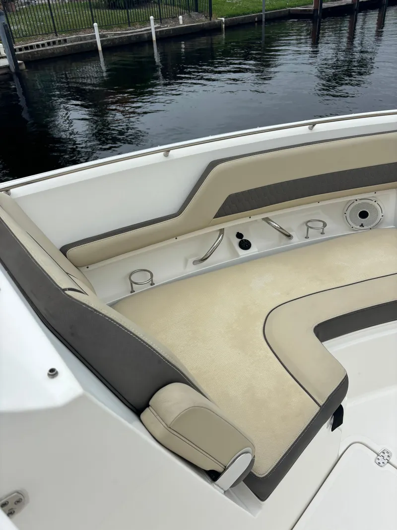 Slide: The Image of 2020 Pursuit 325 Dual Console boat with beige seating, docked by calm water. - 31