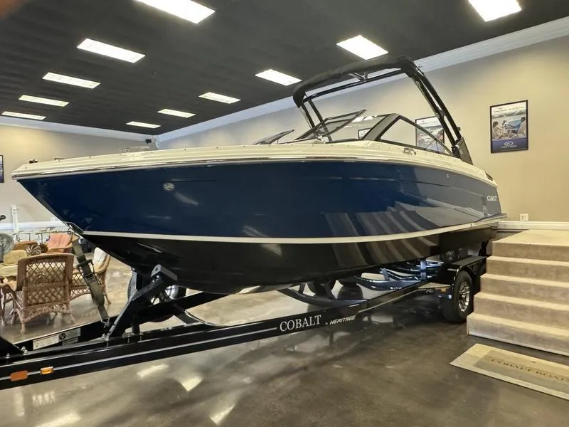 The Image of 2025 Cobalt R6 boat on trailer in showroom, blue and white design. - 1