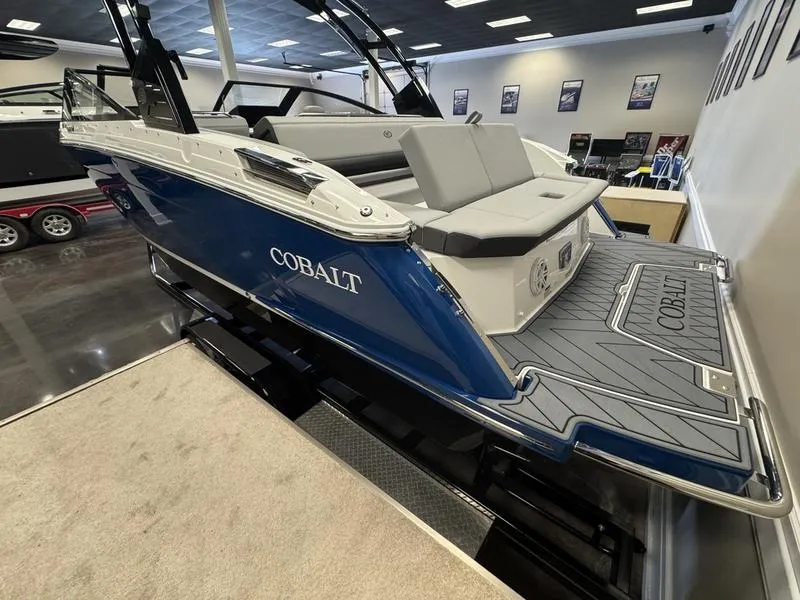 Slide: The Image of 2025 Cobalt R6 boat in showroom, featuring sleek blue and white design. - 13