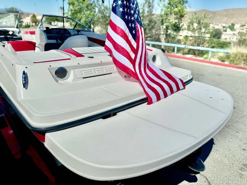 Slide: The Image of 2013 Bayliner 185 Bowrider with American flag, rear view on a sunny day. - 11