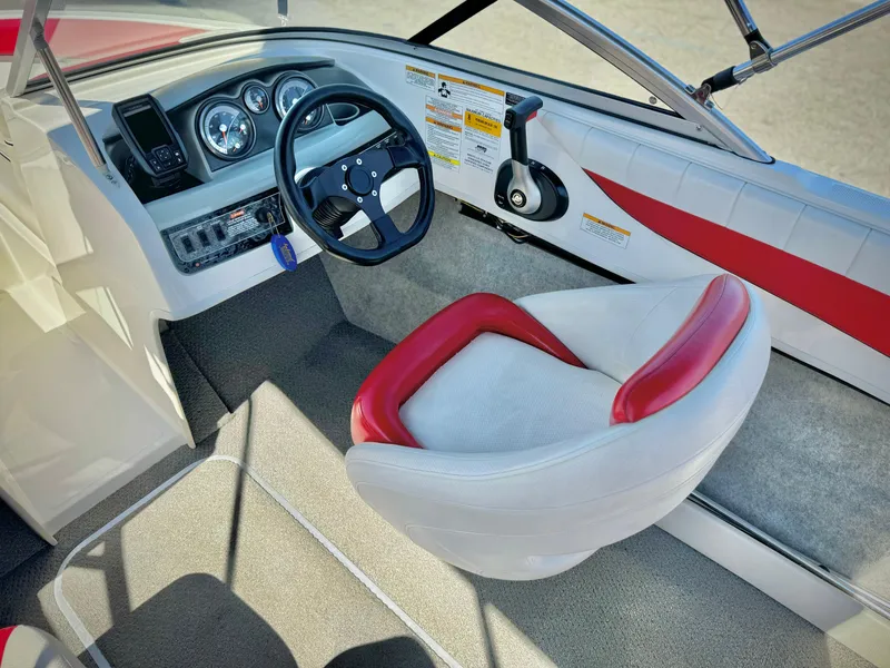 Slide: The Image of 2013 Bayliner 185 Bowrider interior with steering wheel and red-trimmed seat. - 19