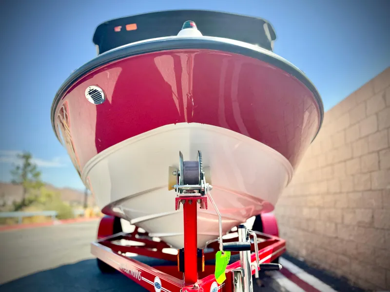 Slide: The Image of 2013 Bayliner 185 Bowrider on trailer, red and white hull, sunny day. - 2