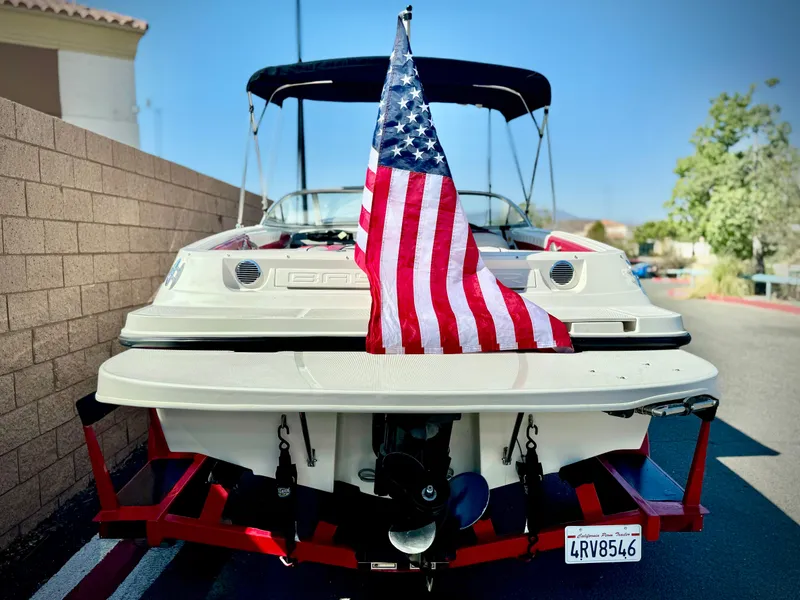 Slide: The Image of 2013 Bayliner 185 Bowrider with American flag on trailer, parked outdoors. - 5