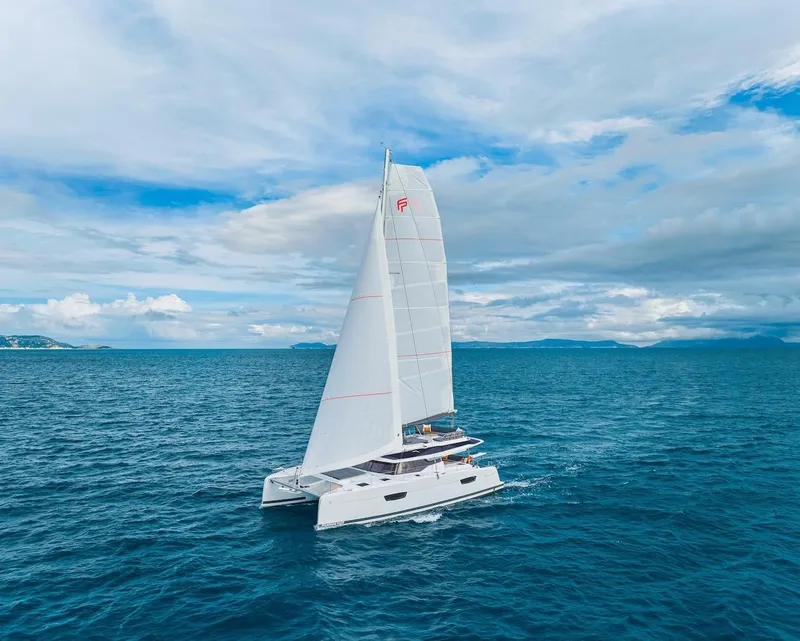 Slide: The Image of 2025 Fountaine Pajot Tanna 47 catamaran sailing on open ocean under a cloudy sky. - 20