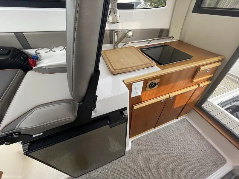 Slide: The Image of 2022 Cutwater C-248 interior with kitchenette, featuring sink, stove, and wooden cabinetry. - 8