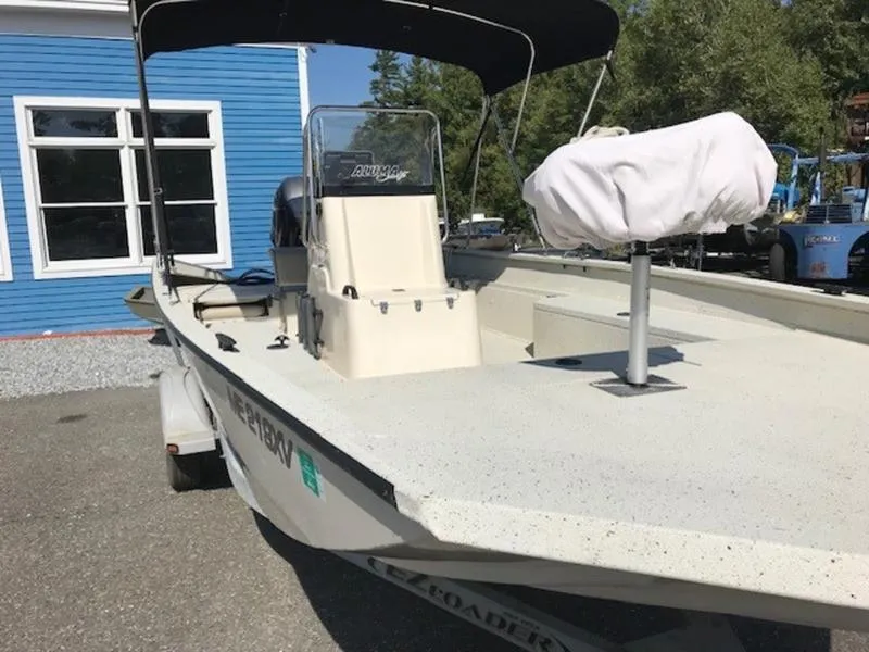 Slide: The Image of 2017 Alumacraft 2072 Bay boat with canopy, parked near a blue building. - 2