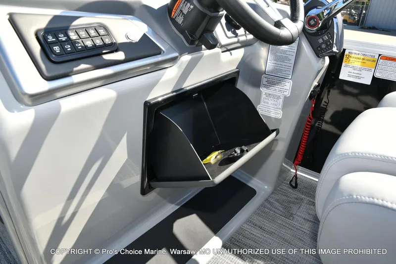 Slide: The Image of 2025 Ranger 243C Cruise boat dashboard with controls and storage compartment. - 50