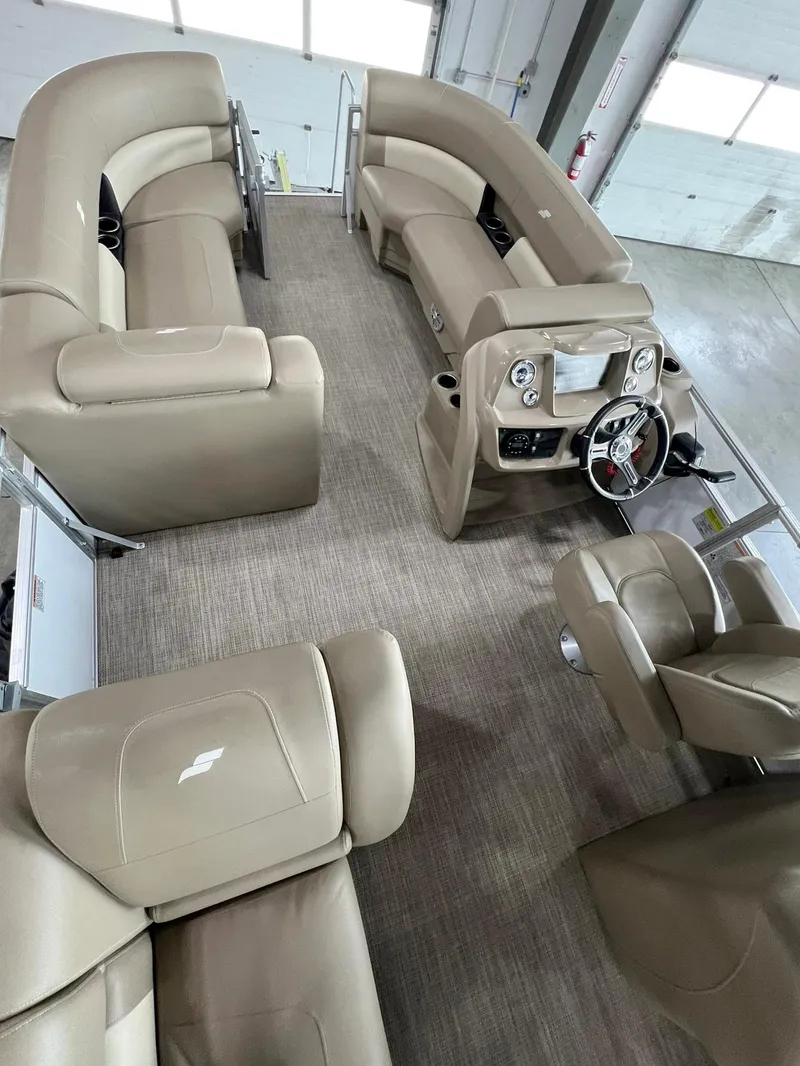 Slide: The Image of 2023 Starcraft LX 22 R pontoon boat interior with beige seating and modern dashboard. - 13