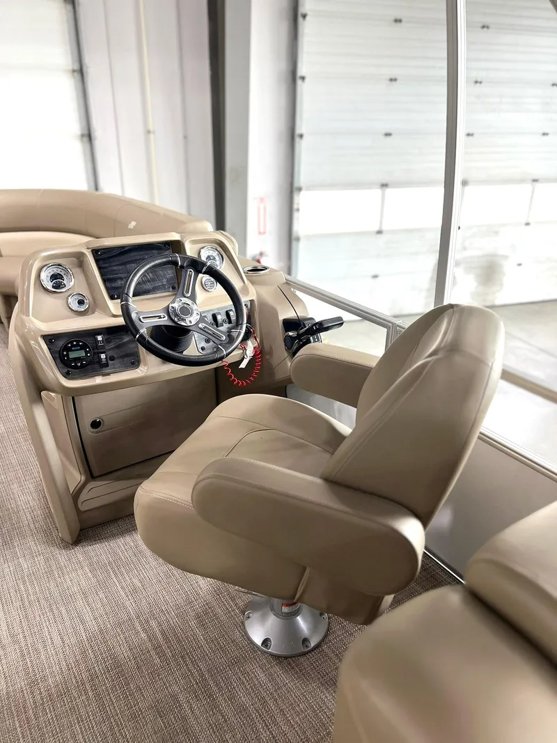Slide: The Image of 2023 Starcraft LX 22 R boat interior with beige captain's chair and control panel. - 2