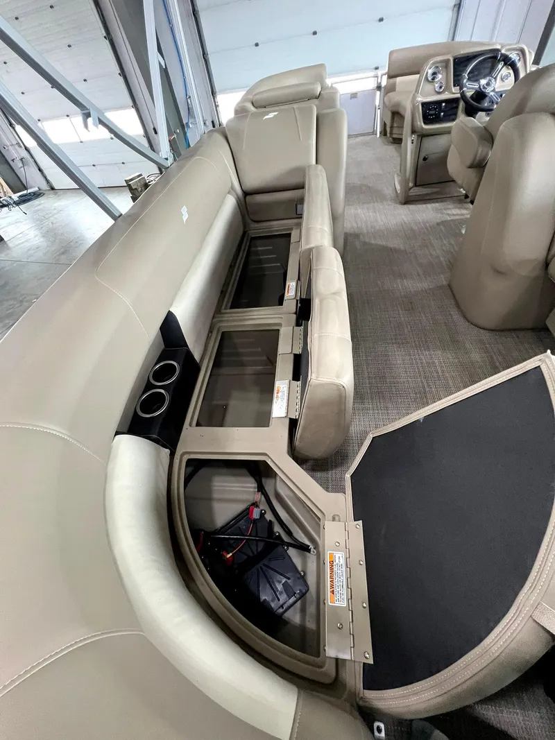 Slide: The Image of 2023 Starcraft LX 22 R boat interior with open storage compartments and beige seating. - 21