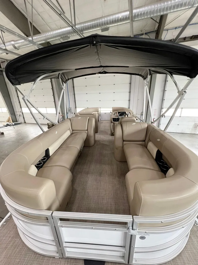 Slide: The Image of 2023 Starcraft LX 22 R pontoon boat interior with beige seating and canopy. - 24