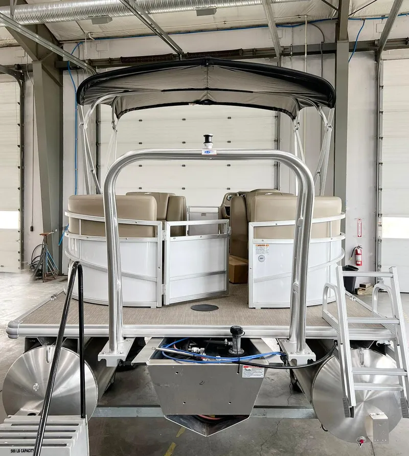 Slide: The Image of 2023 Starcraft LX 22 R pontoon boat in a garage, featuring beige seating and a canopy. - 28