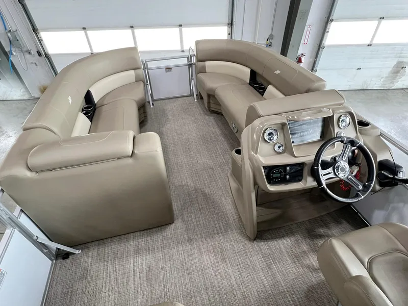 Slide: The Image of 2023 Starcraft LX 22 R pontoon boat interior with beige seating and modern dashboard. - 9