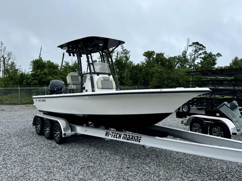 Slide: The Image of 2025 Key West 230BR boat on Hi-Tech Marine trailer, parked on gravel lot. - 2