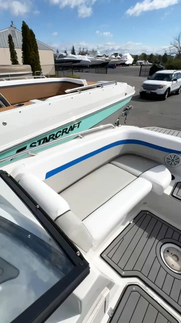 Slide: The Image of 2023 Starcraft SVX 190 OB boat with white and blue seating, docked outdoors. - 2